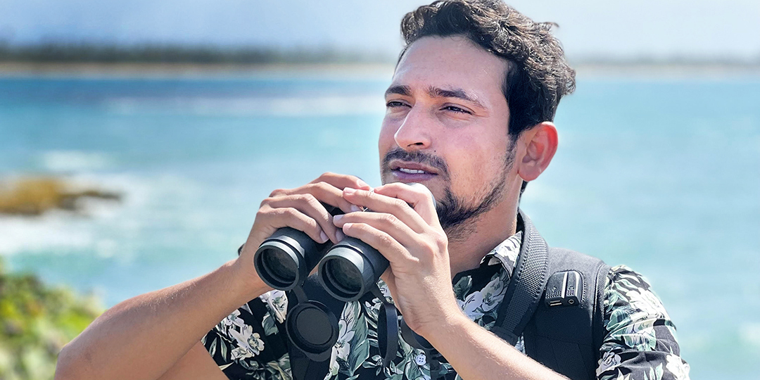 Man bird watching near ocean